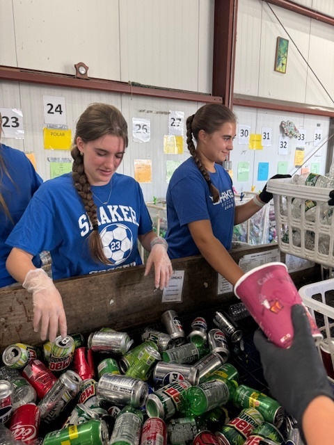 Girls soccer team members helping sort bottles and cans