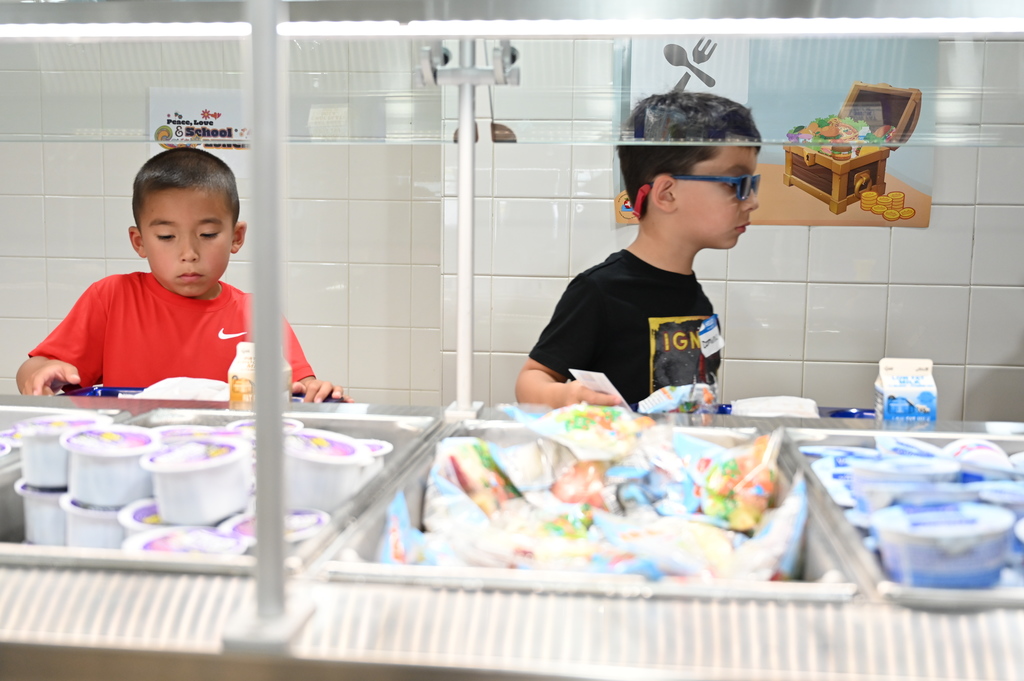 Two students get lunch on the cafeteria line.