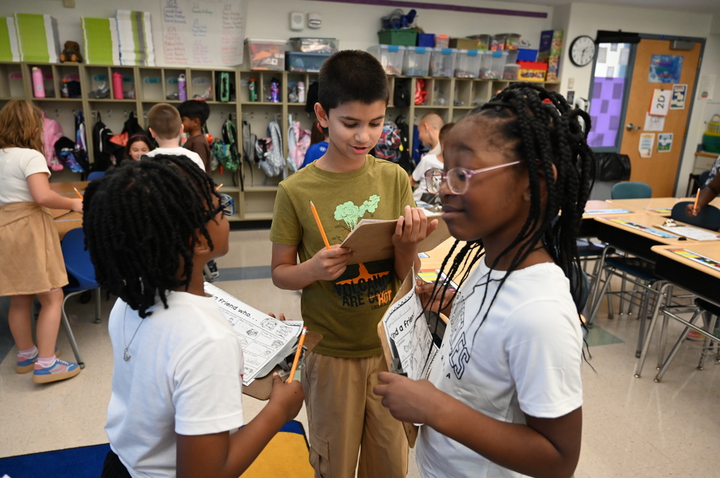 Three students get to know one another by asking questions during a classroom activity.