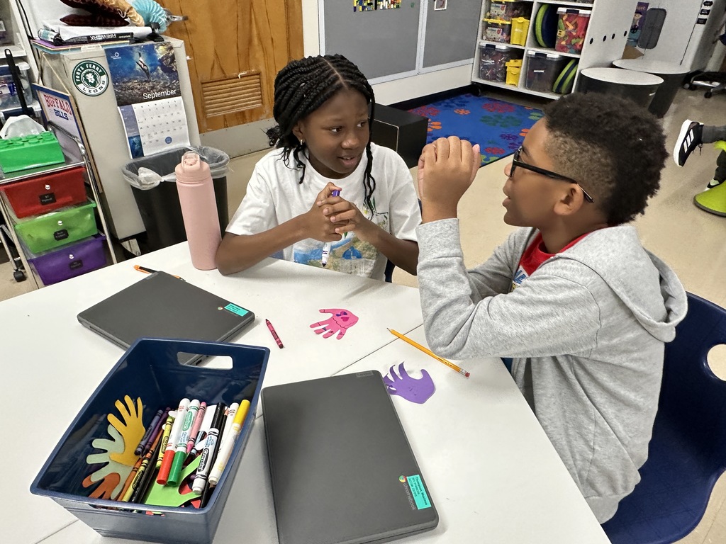 Two students talk at a table in innovation lab.