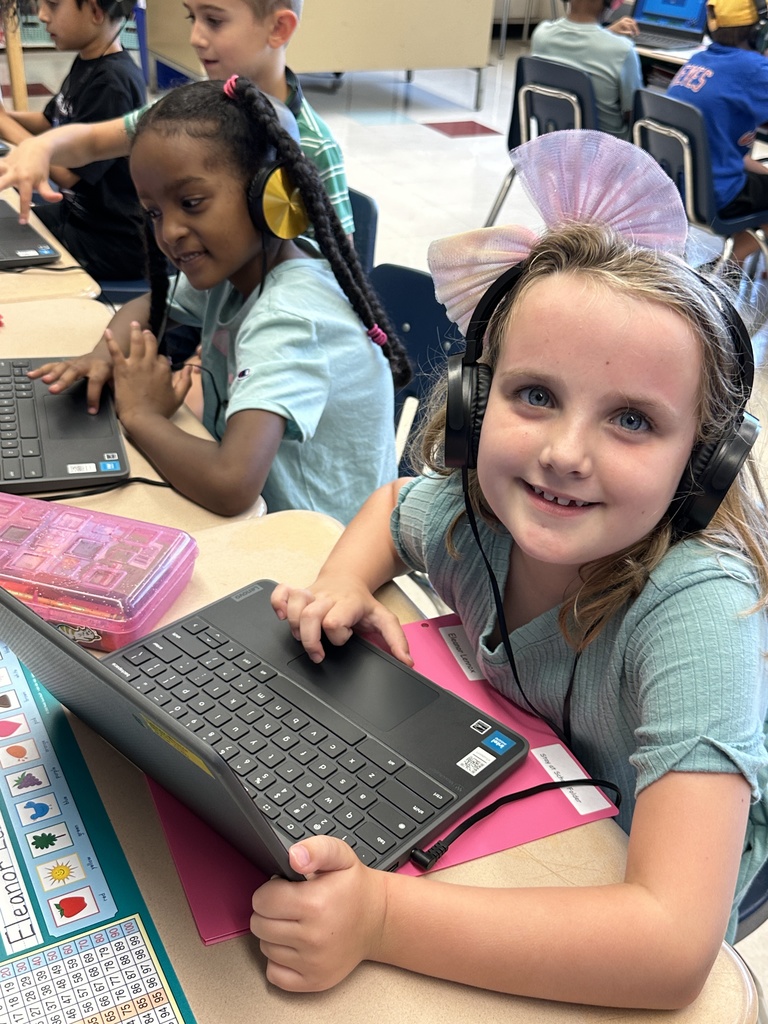 Students wearing headphones work at their Chromebooks.