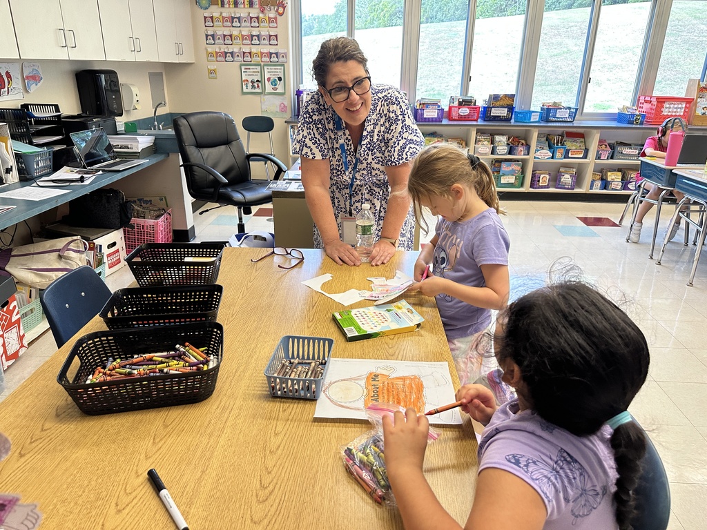Superintendent Kathleen Skeals speaks to two students as they color and cut out a project.