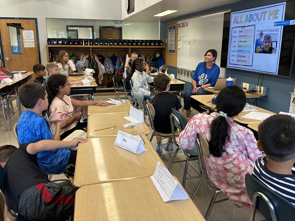 Students look toward the teacher at the front of the room as she goes through a student's presentation.