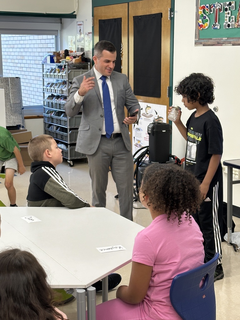 Meterologist Chris Gilson gets help from a student for a science experiment as other students look on.