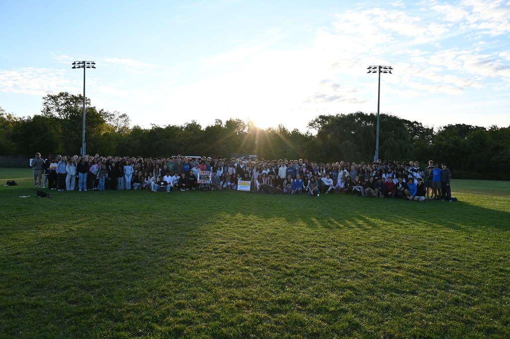 Members of the Shaker Class of 2026 pose as a large group in front of the sunrise.