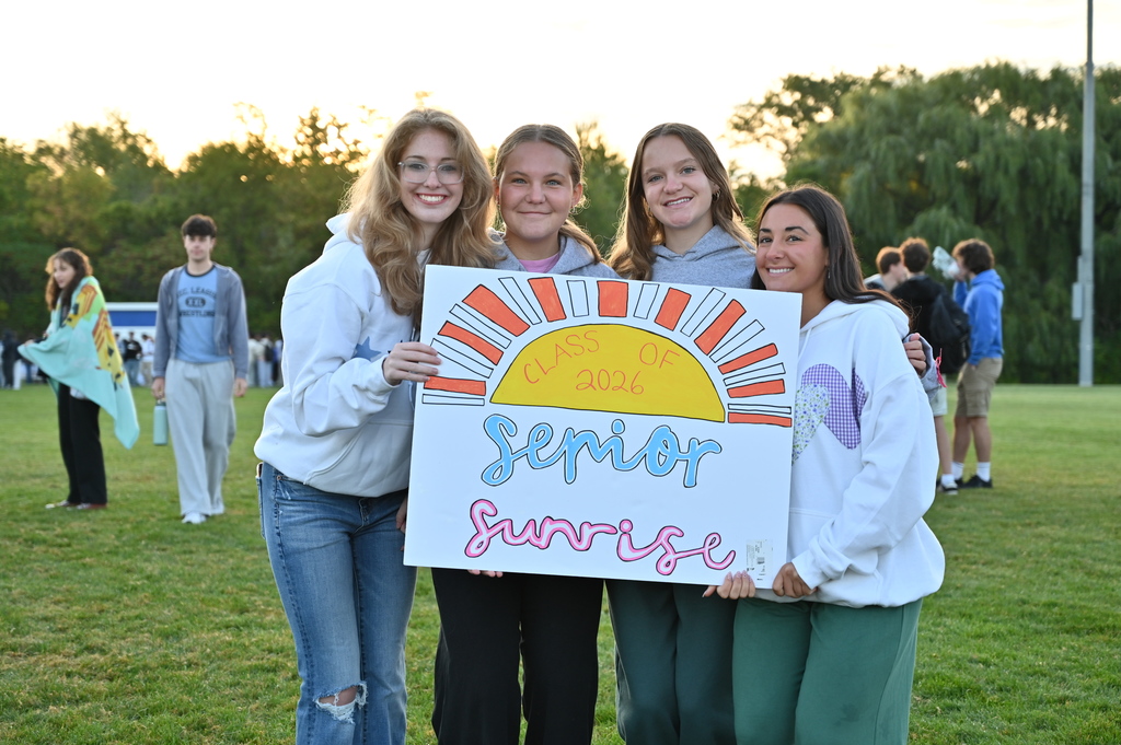 Four students pose with a sign that says "Class of 2026 Senior Sunrise."
