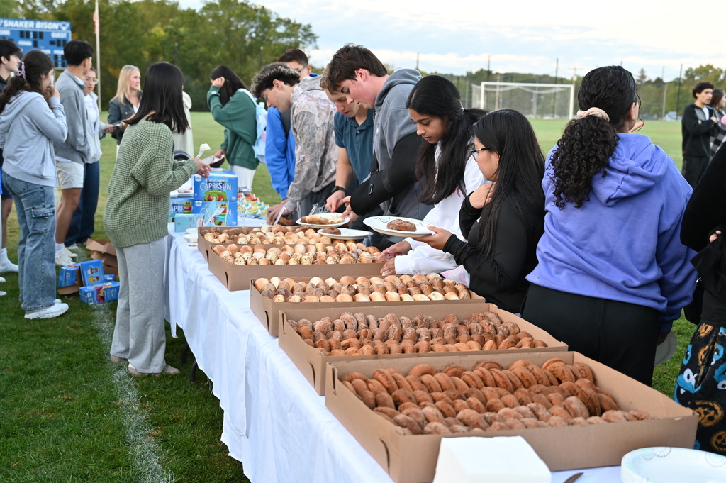 Students take bagels and donuts from a line of tables.