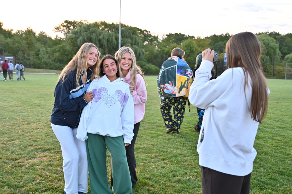 Three students pose as another student takes their picture.