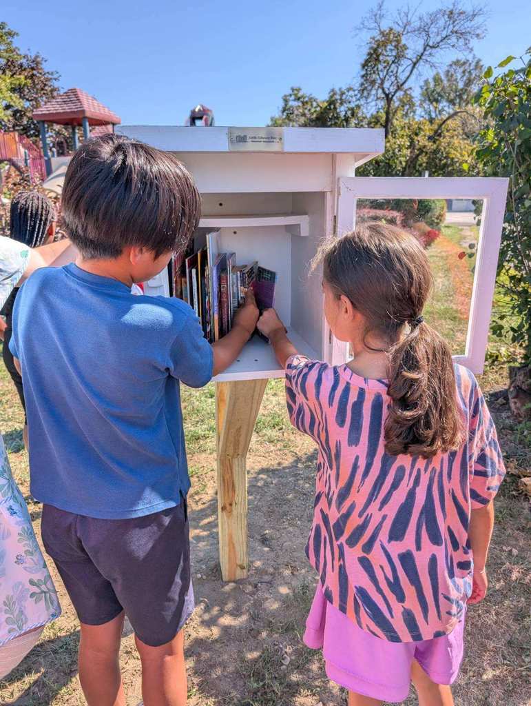 Fourth grade students place books in the Little Free Library.