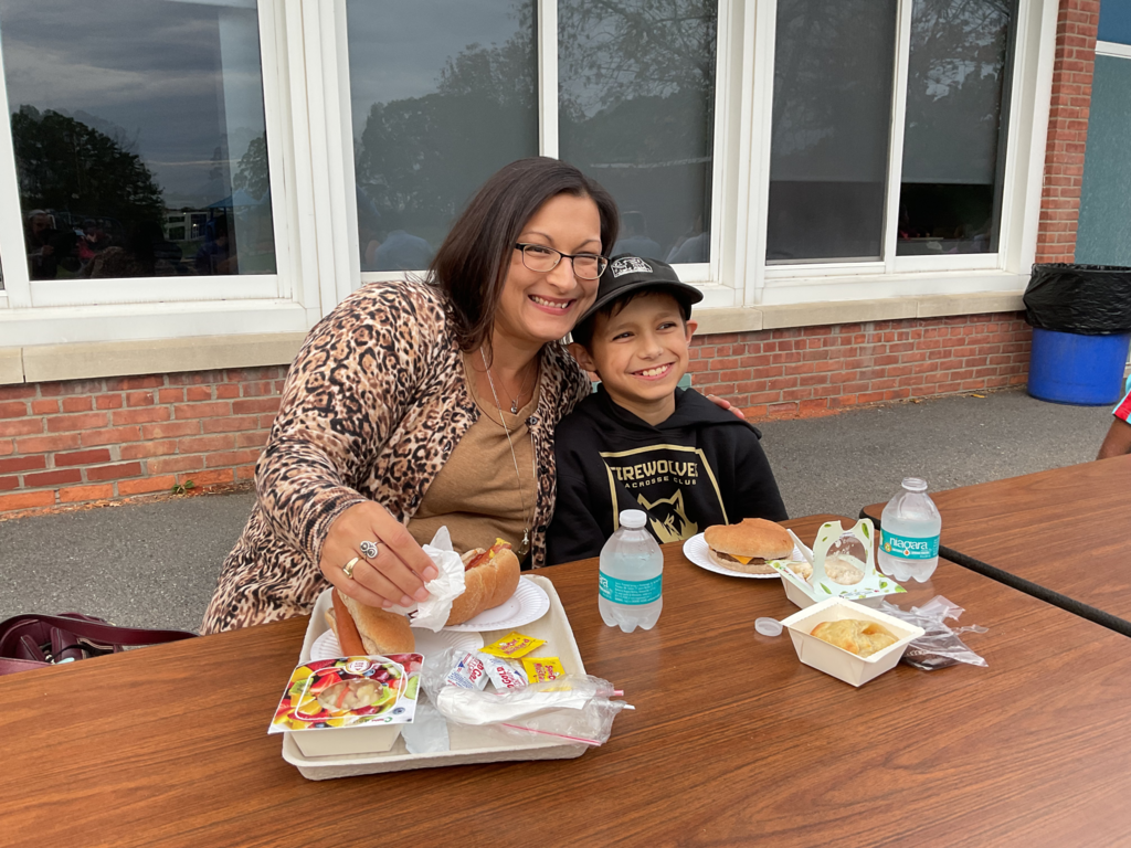 Two people pose at a table with food in front of them.