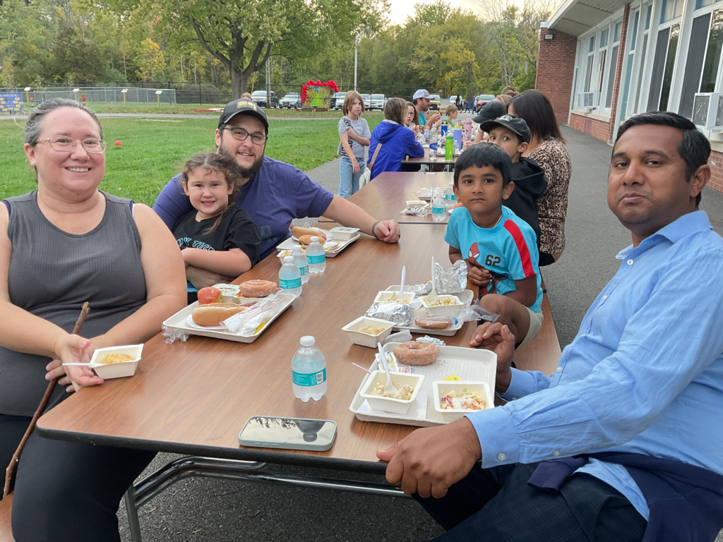 A group of people sits at a table with food in front of them.