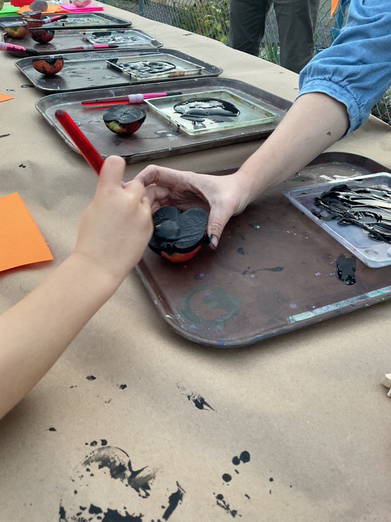 An image of a hand painting half of an apple black to use it as a stamp.