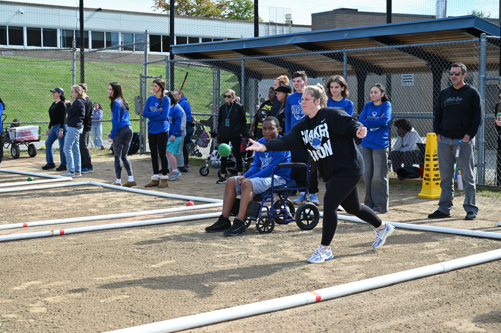 A Shaker faculty member tosses a bocce ball as others behind her watch.