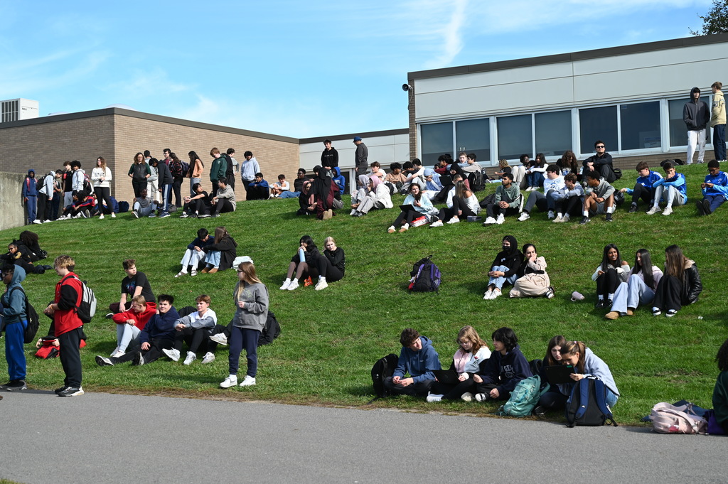 Dozens of students sit on the grassy hill and watch the competition.