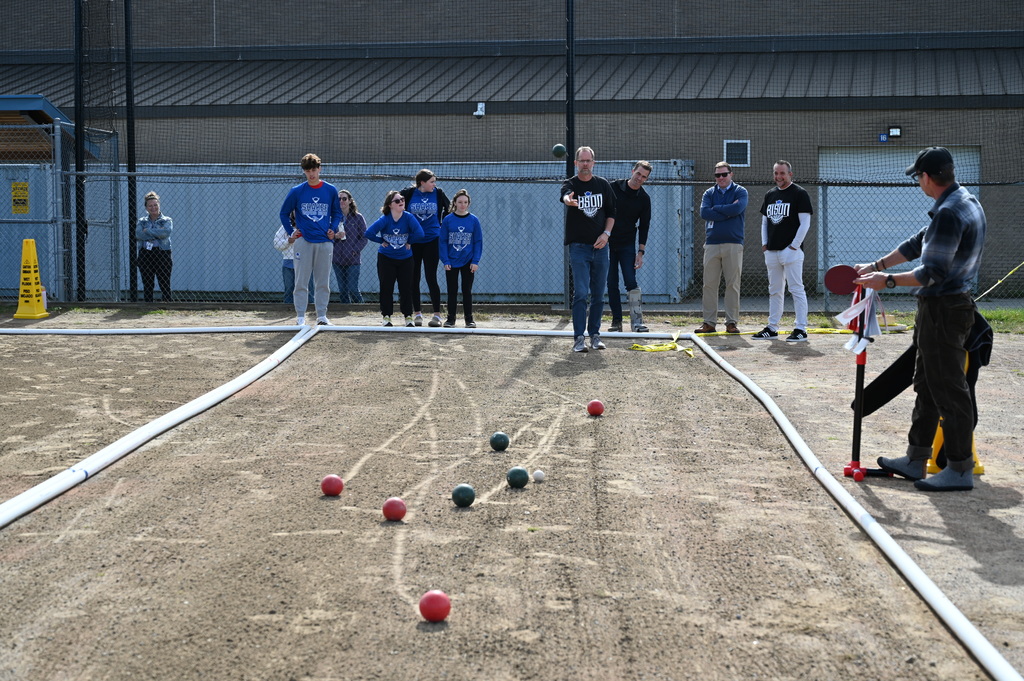A Shaker faculty member tosses the ball as others behind him watch.