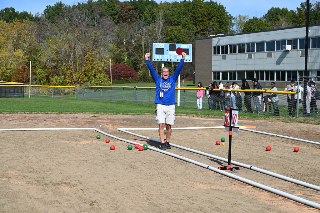 A Unified bocce coach celebrates a great shot with his arms in the air.