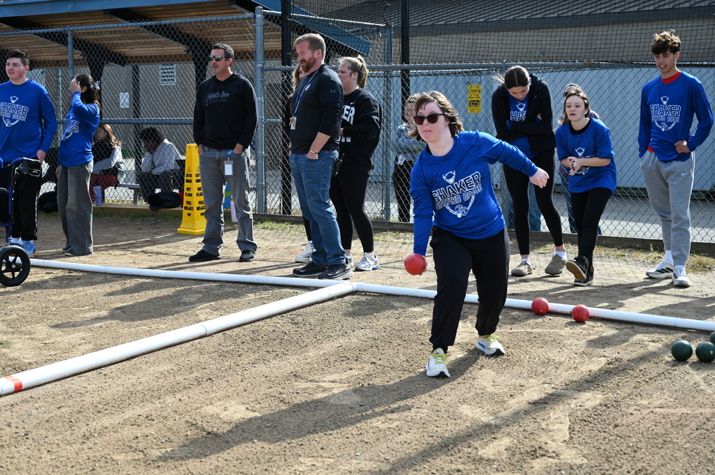 A Unified bocce player takes aim with a bocce ball in hand.