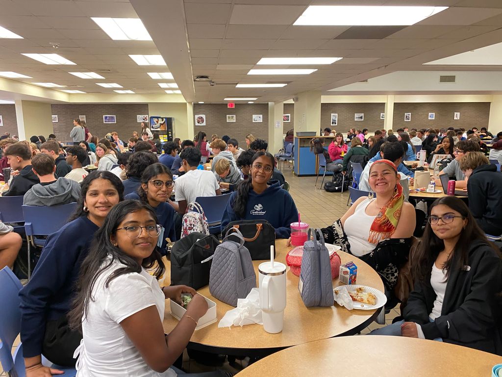 Students sit around a table eating breakfast together.