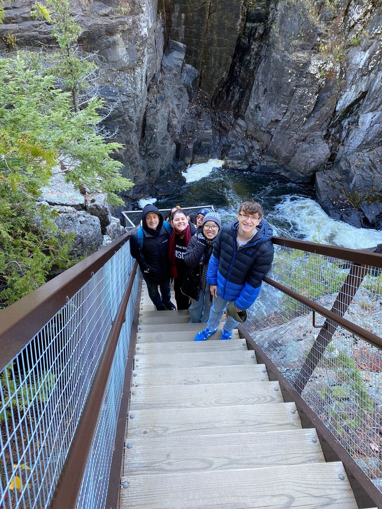 People pose on a stairway with a beautiful gorge behind them.