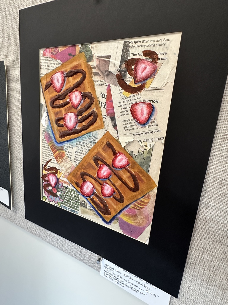 A work of art on display that shows waffles with strawberries on them with newspaper clippings in the background.