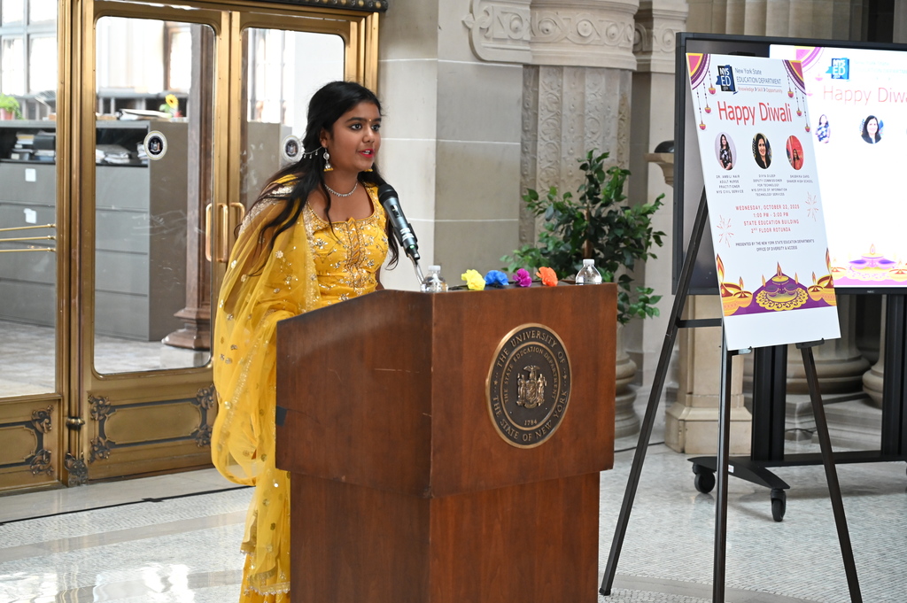 Shaker freshman Shubhika Garg stands at a podium reading  a proclamation.