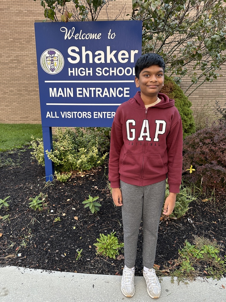 An image of Shaker freshman Sharvesh Srinivasan standing in front of the Shaker High School main entrance sign outside.