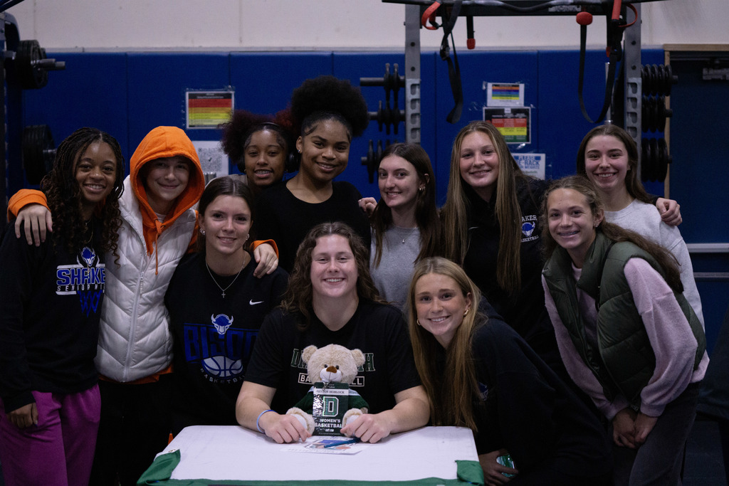 Members of the Shaker girls basketball team surround one of their teammates after she signed her letter of intent.