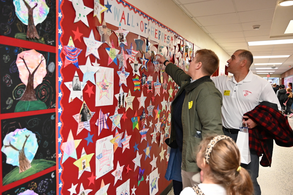 Military members look at Boght Hill's Wall of Heroes