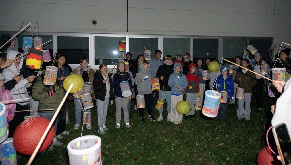 Dozens of students pose in front of Shaker Middle School with lanterns for Martinstag.