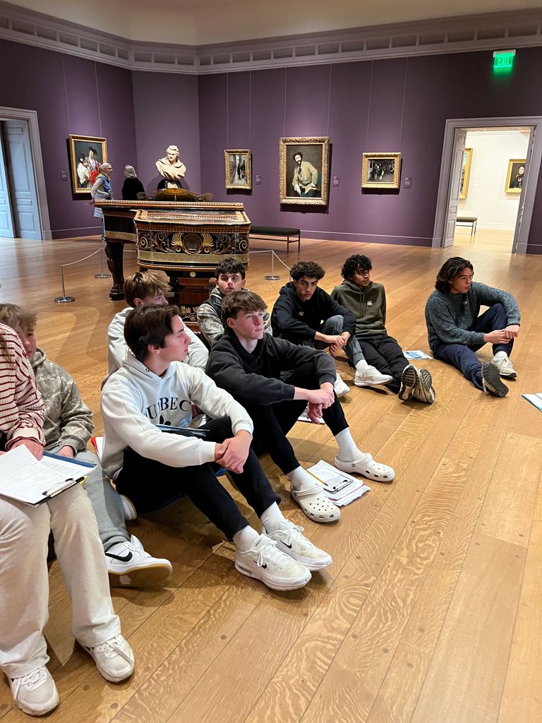 Students sit on the floor of a museum.