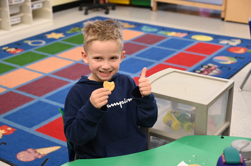 A student gives thumbs up after tasting the butter he made in class with a cracker.