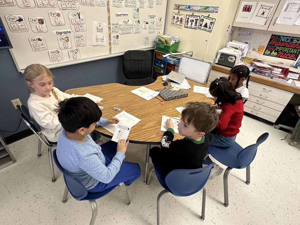 Five students sit at a table and fill out their ballots.