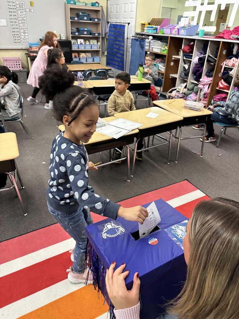 One student smiles as she places her ballot in a ballot box.