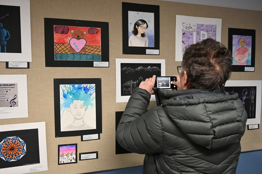 A person takes a photo of a work of art in a gallery.