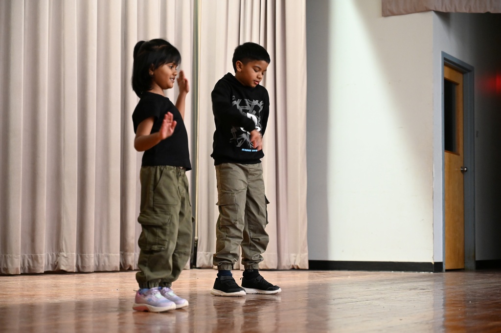Siblings perform a dance routine on stage.