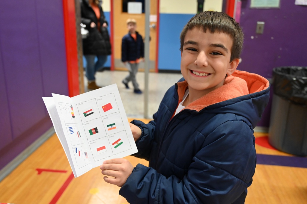 A student smiles as he shows off his passport filled with stamps from different countries.