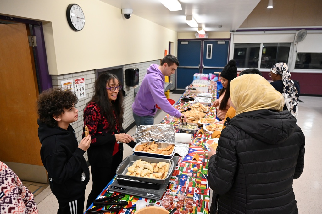 People sample a variety of cuisines from a long table.