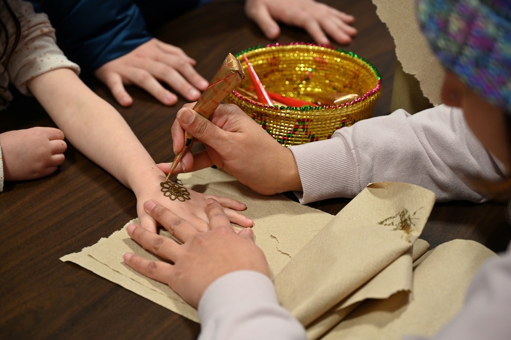 A students gets a henna tattoo on her hand.