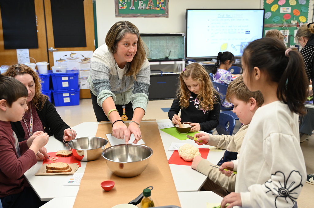 Mrs. Cost helps Forts Ferry student prep vegetables