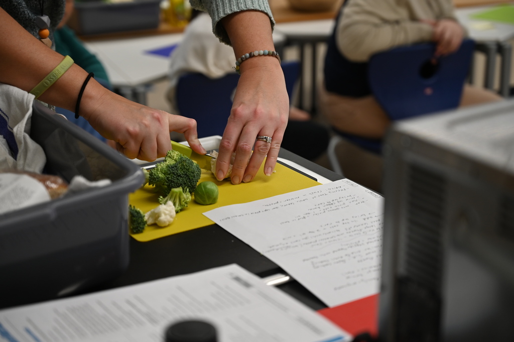 Mrs. Cost shows students the proper way to cut vegetables