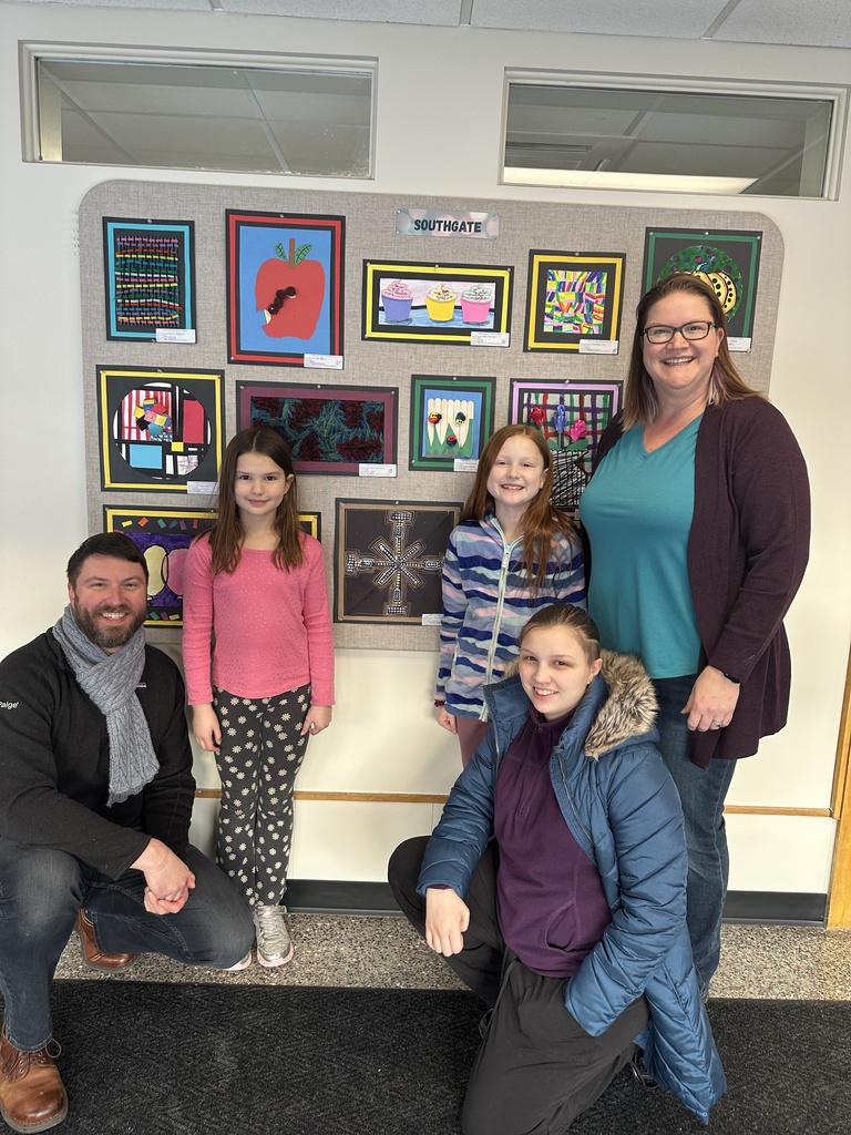 A family poses next to student artwork on display.