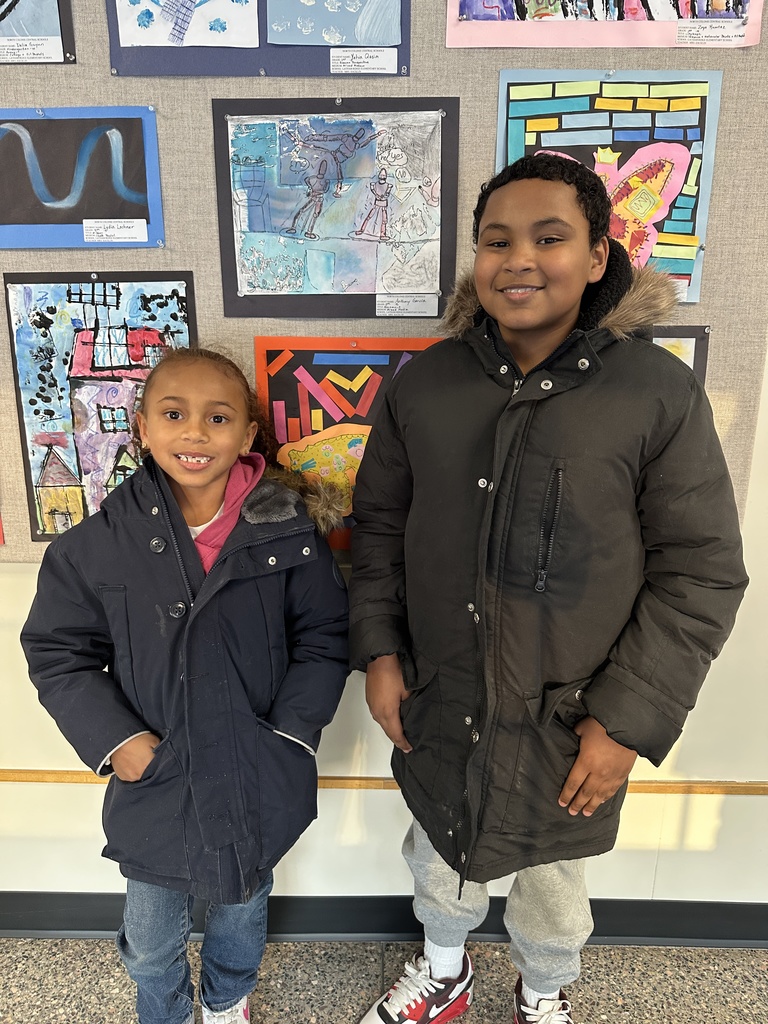 A student and his sibling pose next to his artwork on display in the gallery.