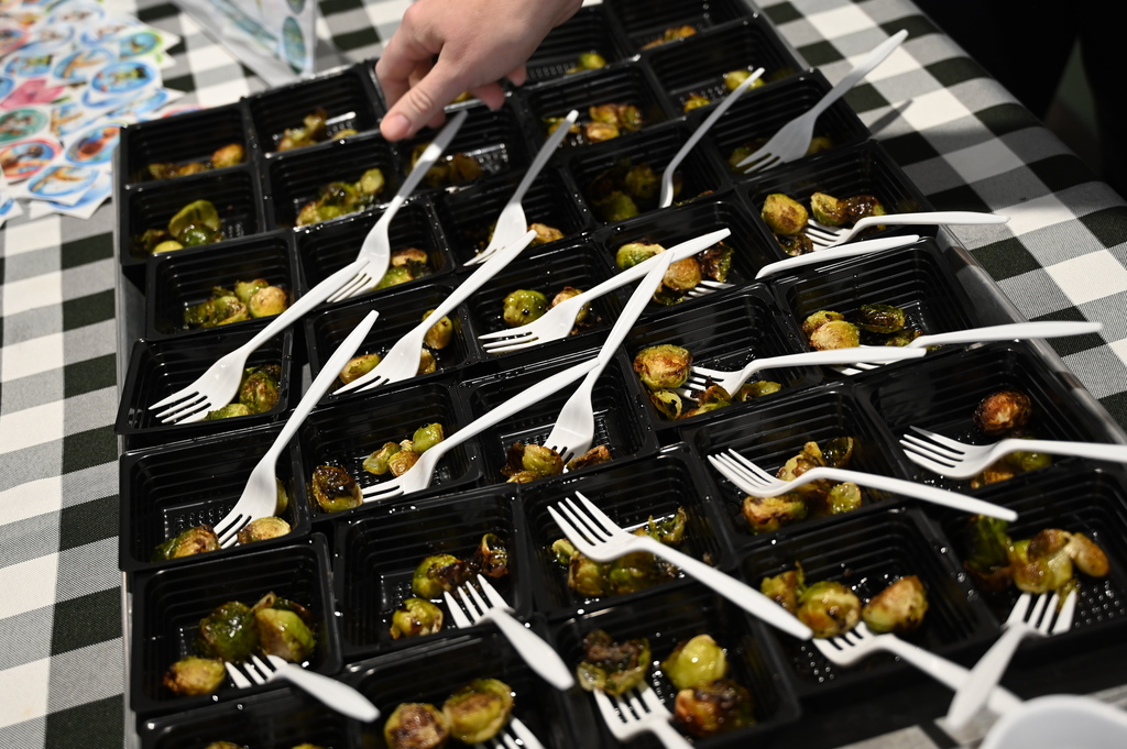 Samples of Brussels sprouts on a tray with forks in each of the individual dishes.