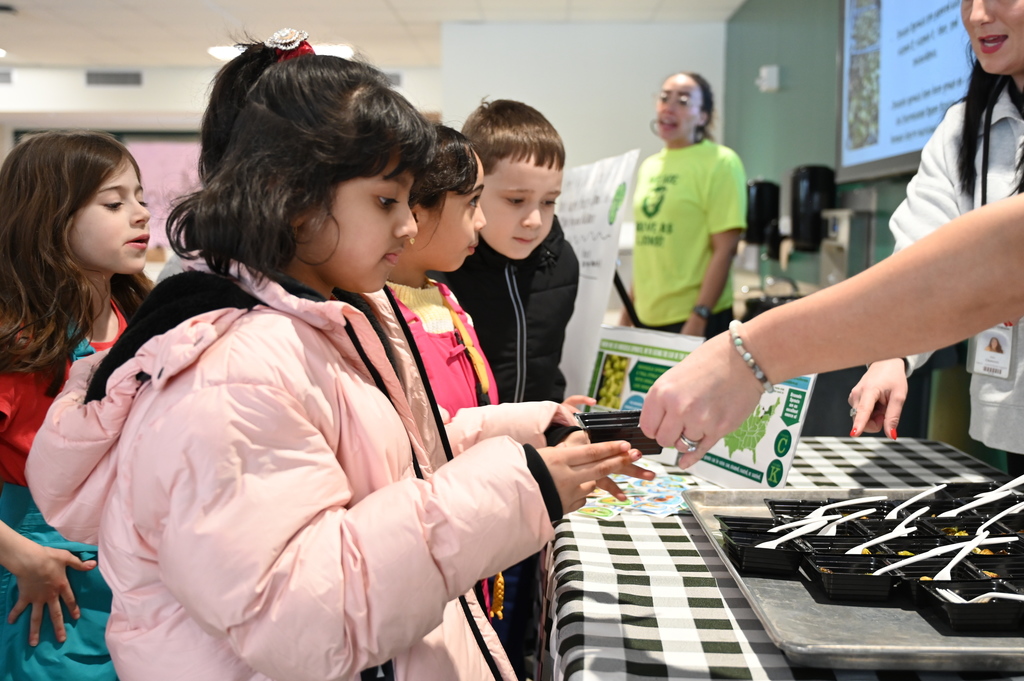 Students are handed Brussels sprouts samples from members of our Food Service team.