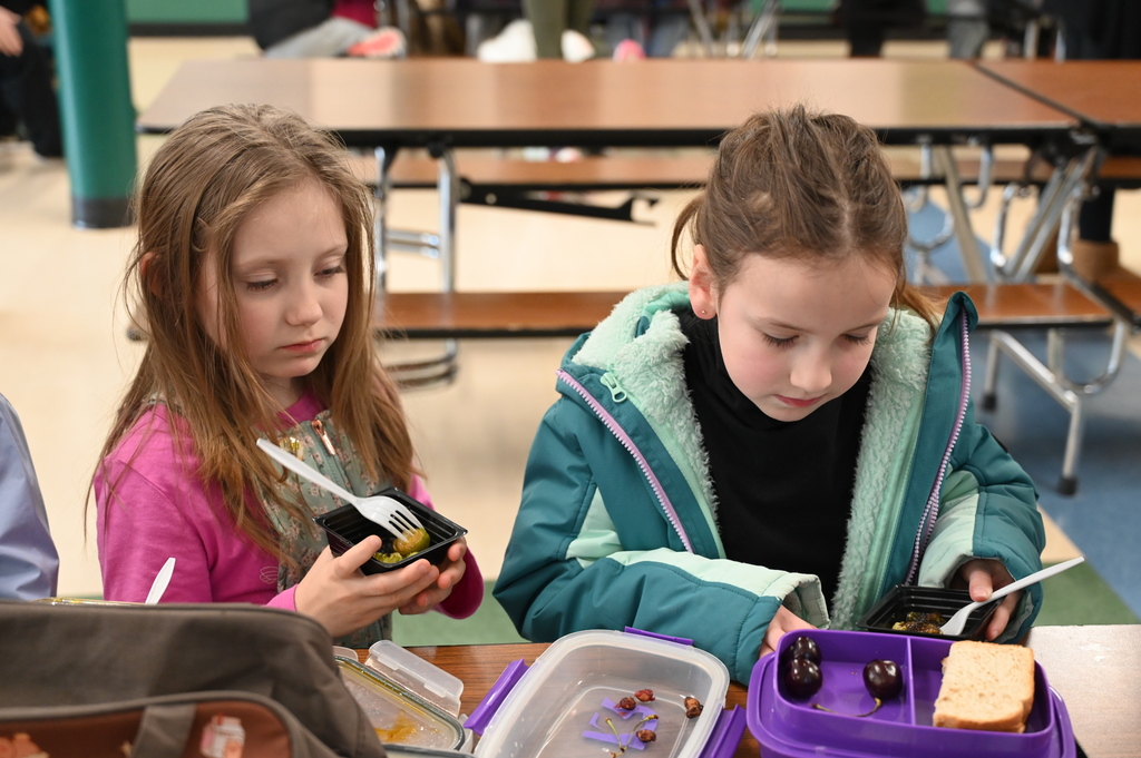 Two students taste Brussels sprouts at their lunch table.