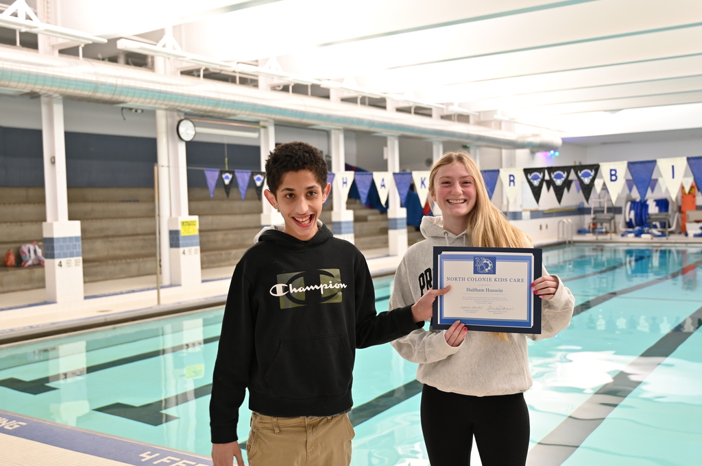 Two students pose with their Kids Care certificate in front of the pool.
