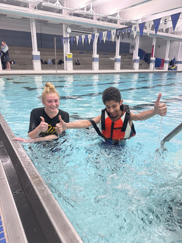 Two students give thumbs up from in the pool, celebrating Haitham's achievement!
