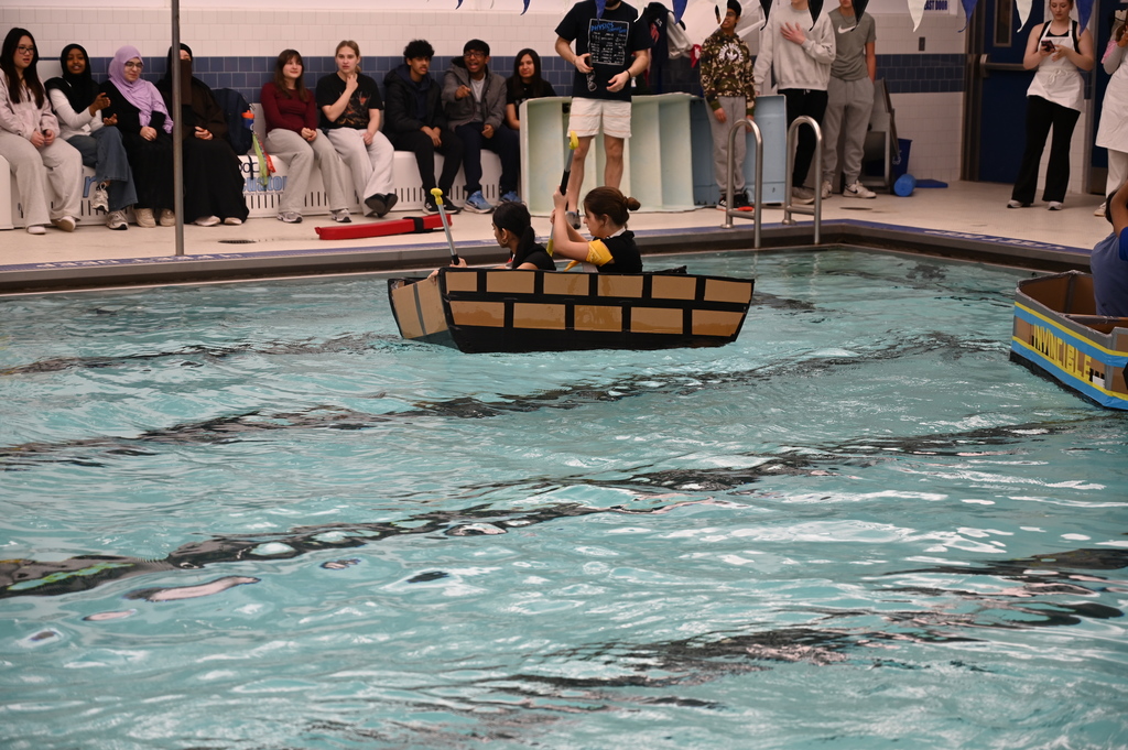 Students in the "Taco Express" cardboard boat move along