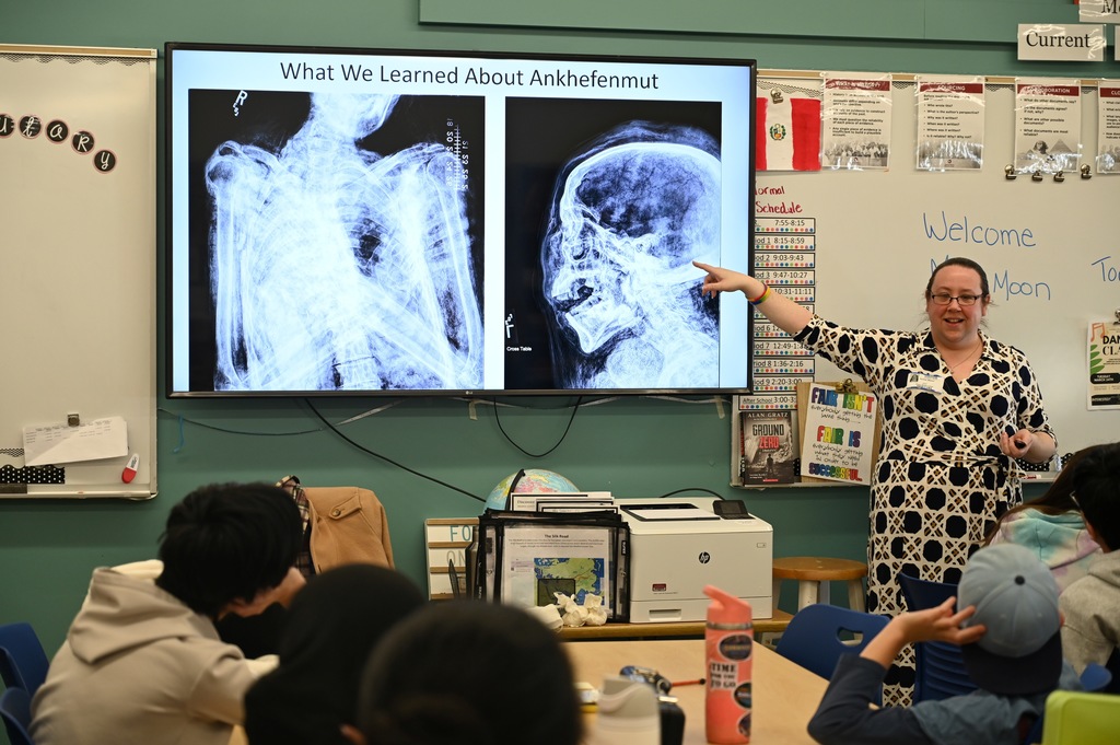 Ms. Moon, from the Albany Institute, points to an x-ray of a human skull on a TV screen.