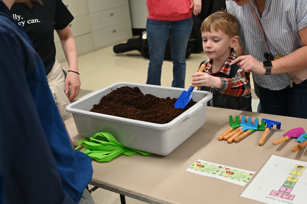 A student uses a hand shovel to dig in the dirt.